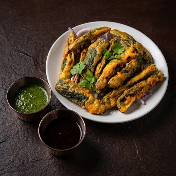 Crispy fried okra pakora with cilantro garnish, served with green and dark dipping sauces.